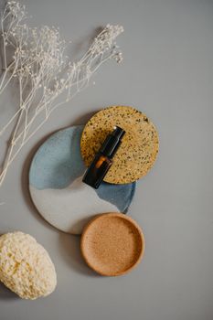 Flat lay of spa essentials including essential oil and pumice on ceramic plates for a relaxing ambiance.