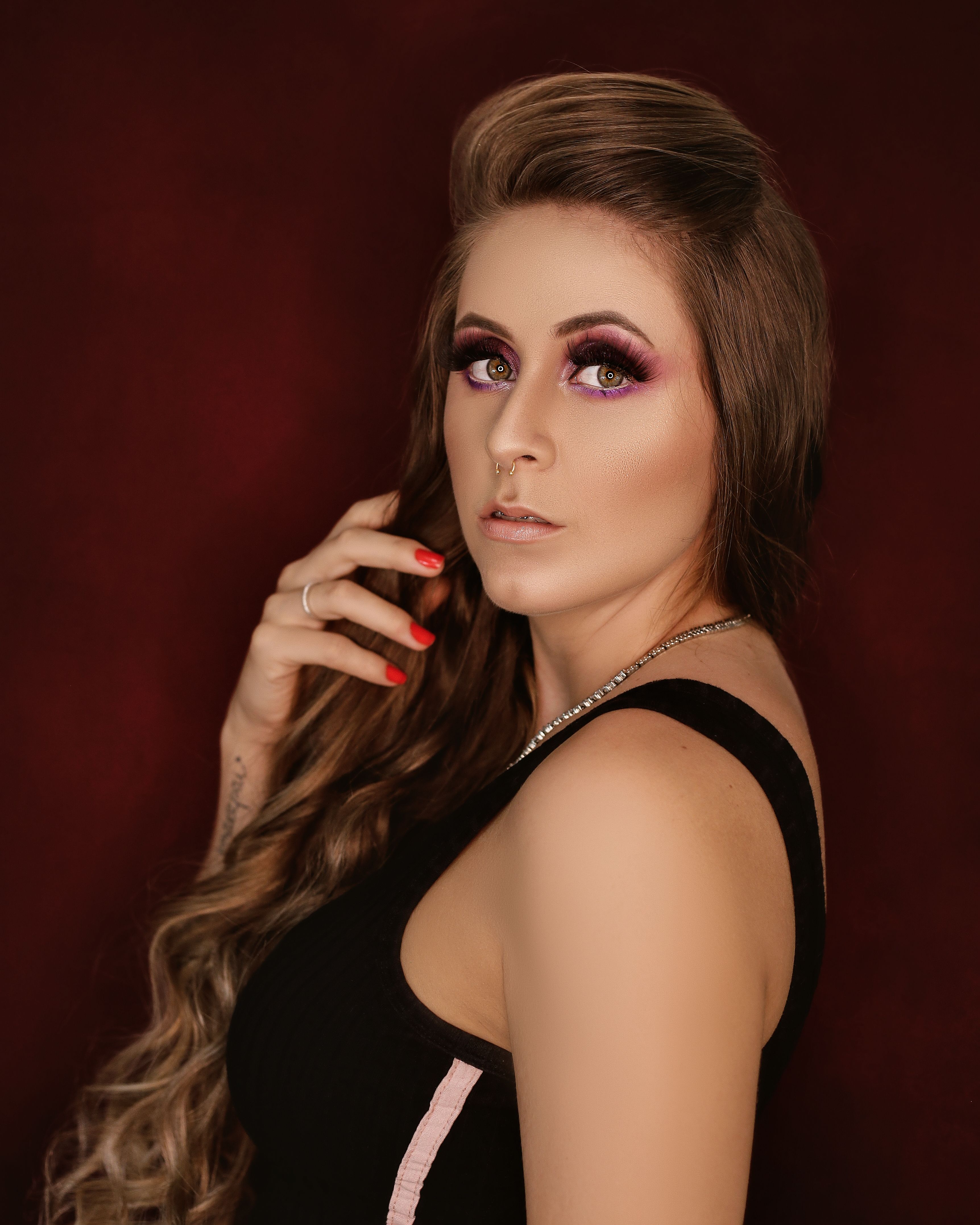 Portrait of a stylish woman with long hair, bold makeup, and a confident gaze.