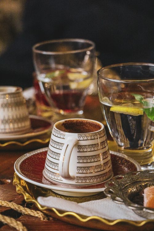 Free Close-up of Ankara-style coffee cup on a wooden table with refreshing lemon water and sugar cubes. Stock Photo