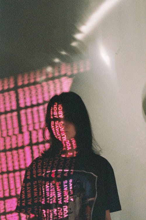 Millennial woman with letters on face in pink light