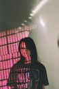 Millennial woman with letters on face in pink light