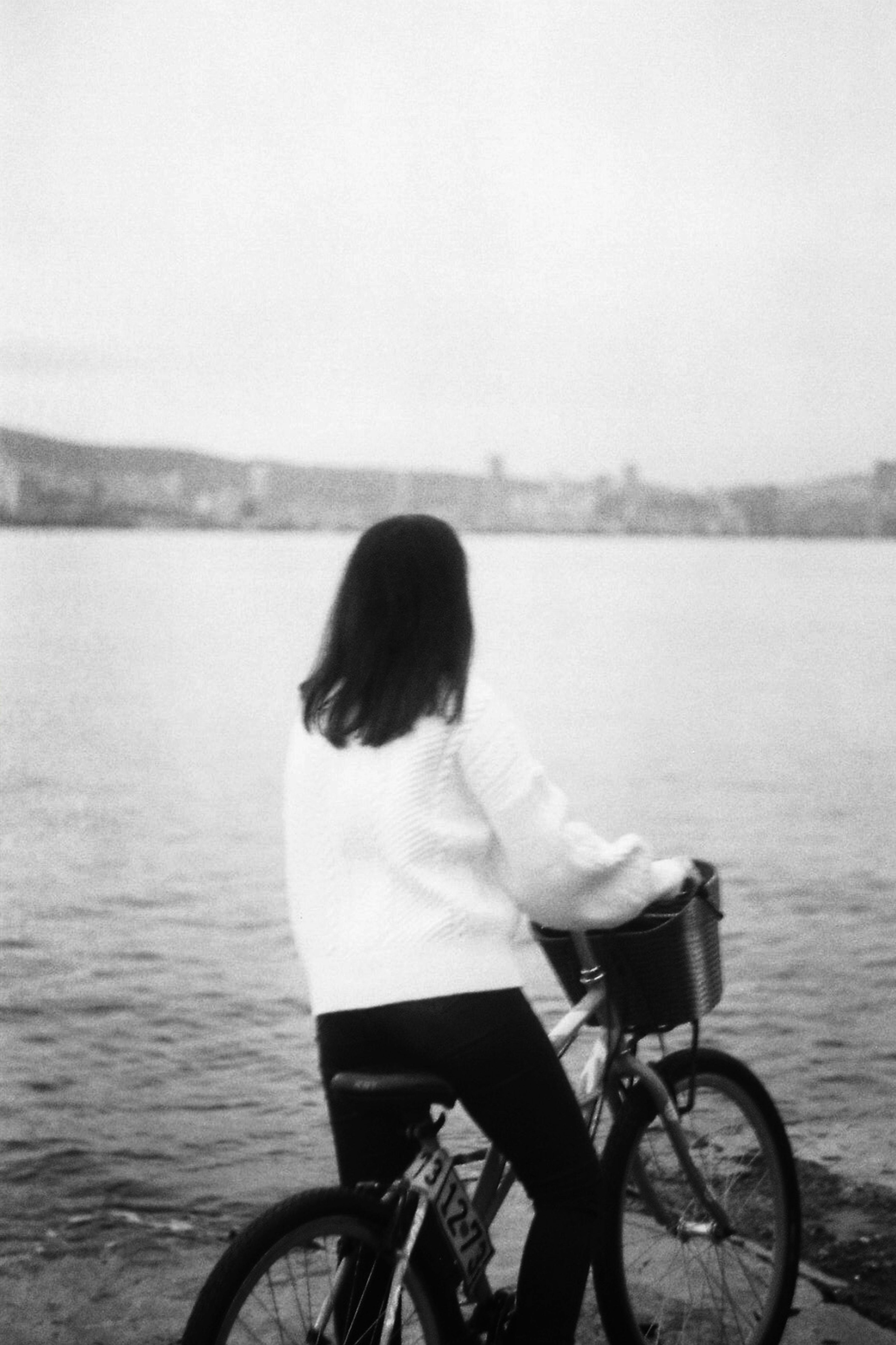 woman on bicycle on river coast