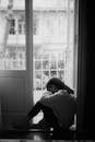 Sad woman sitting in doorway of balcony