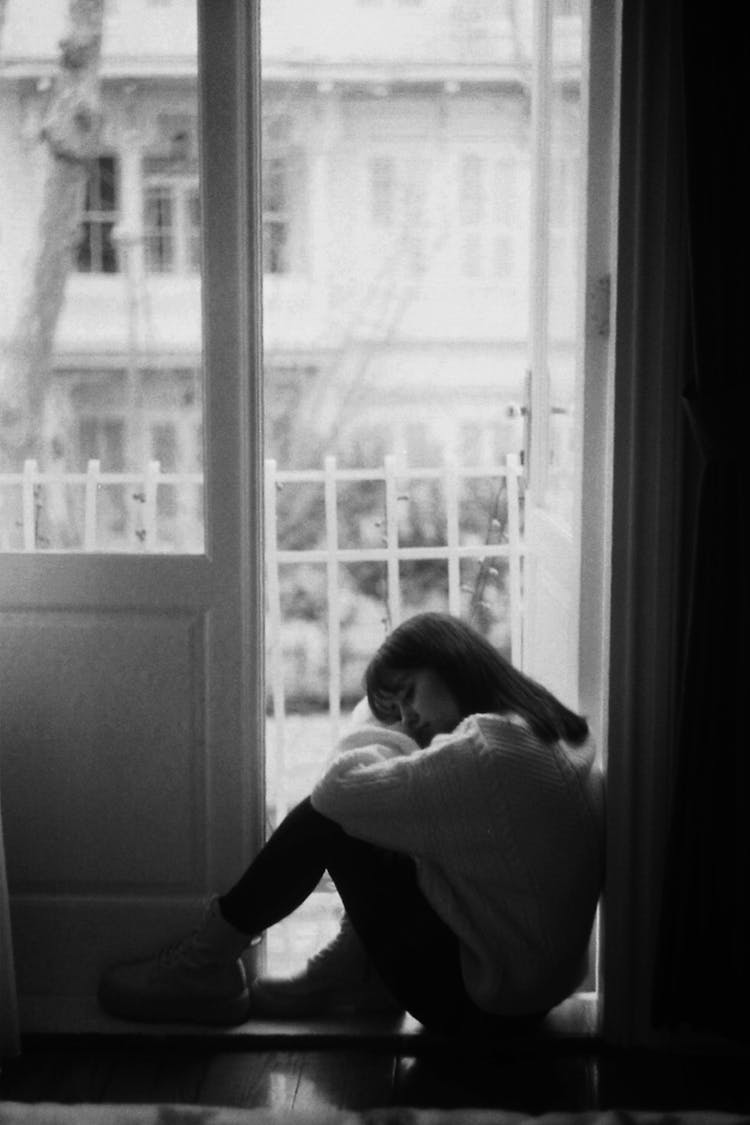 Sad Woman Sitting In Doorway Of Balcony