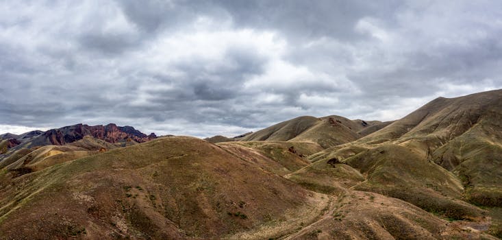 Scenic view of rugged rolling hills and mountains with dramatic cloudy skies.