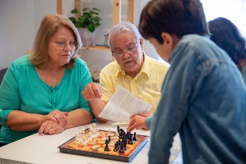 Free A joyful family moment as grandparents and grandson enjoy a game of chess together. Stock Photo