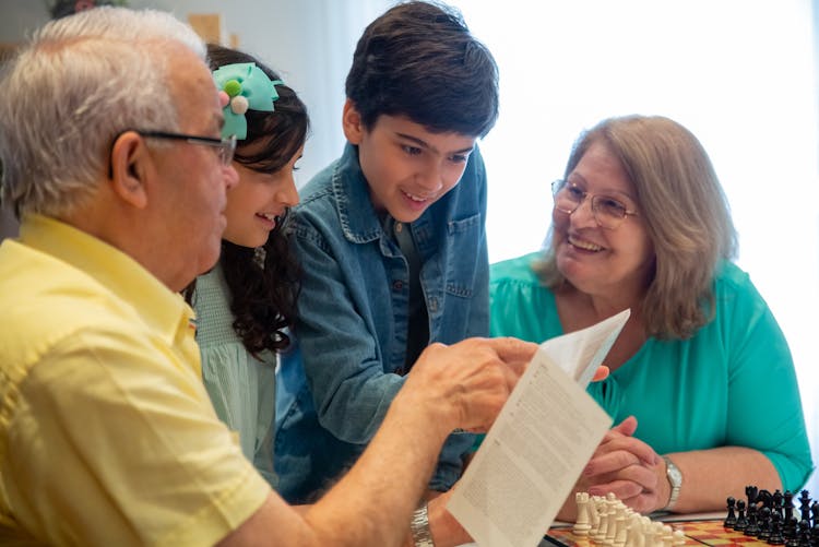 Man And Children Looking At A Paper