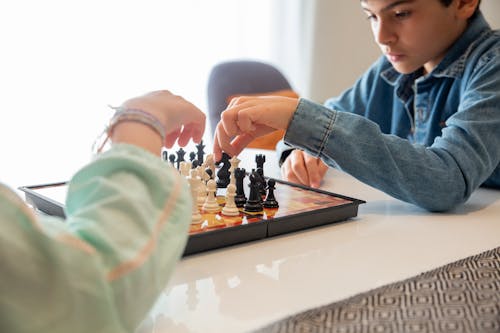 Person in Blue Denim Jacket Playing Chess