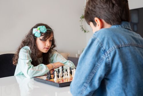 Free Children focused on a chess game at home, fostering strategic thinking. Stock Photo