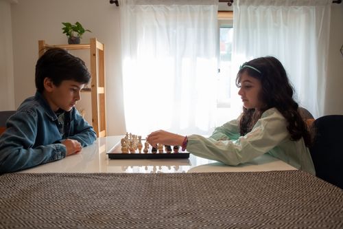 Free Two children engaged in a chess game indoors, captured in Portugal. Stock Photo