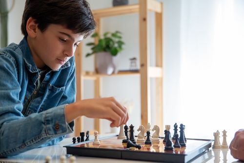 Free Young boy deeply focused while playing chess indoors, showcasing strategic thinking. Stock Photo