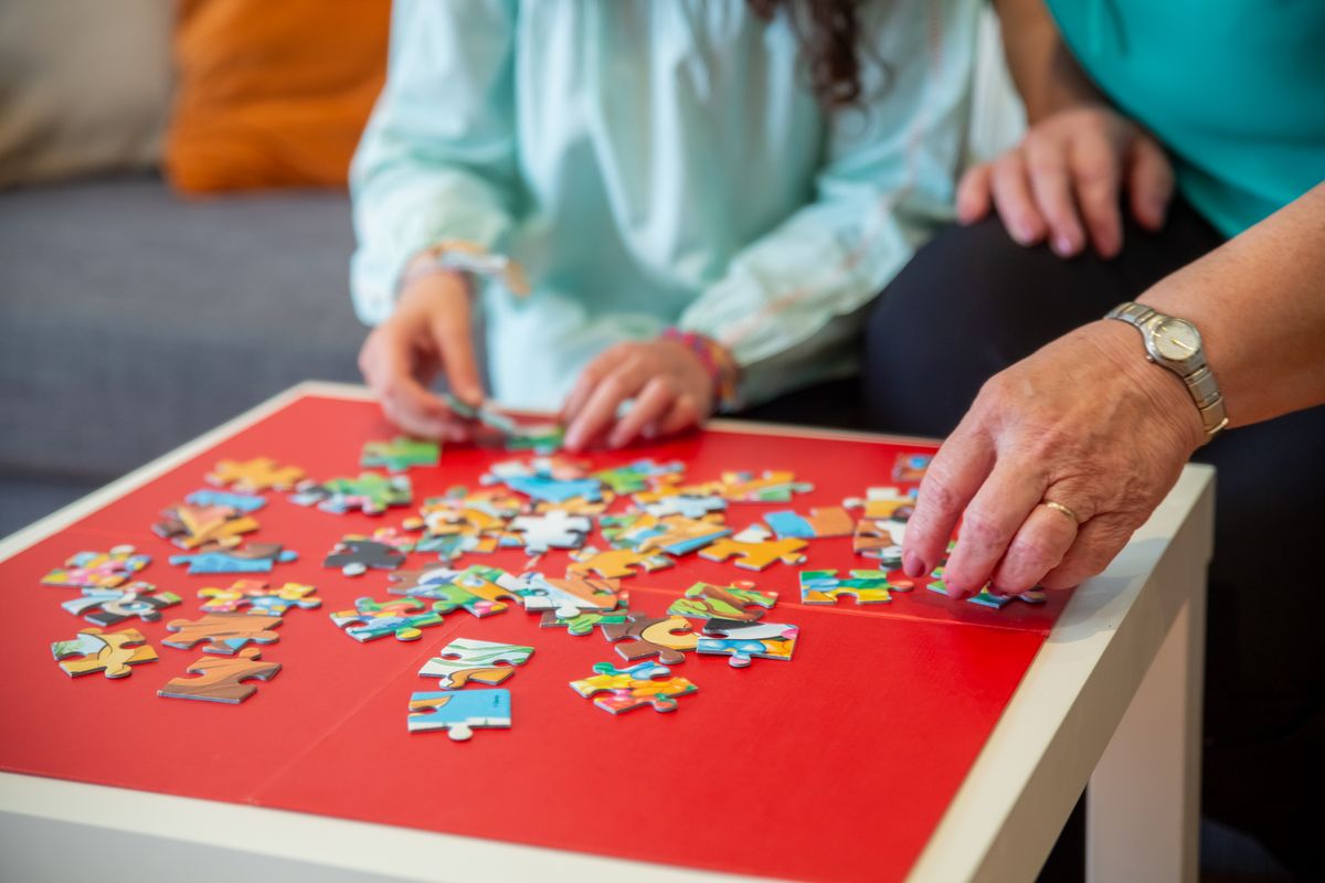 Hands working together on a colorful jigsaw puzzle indoors, party games for adults without alcohol