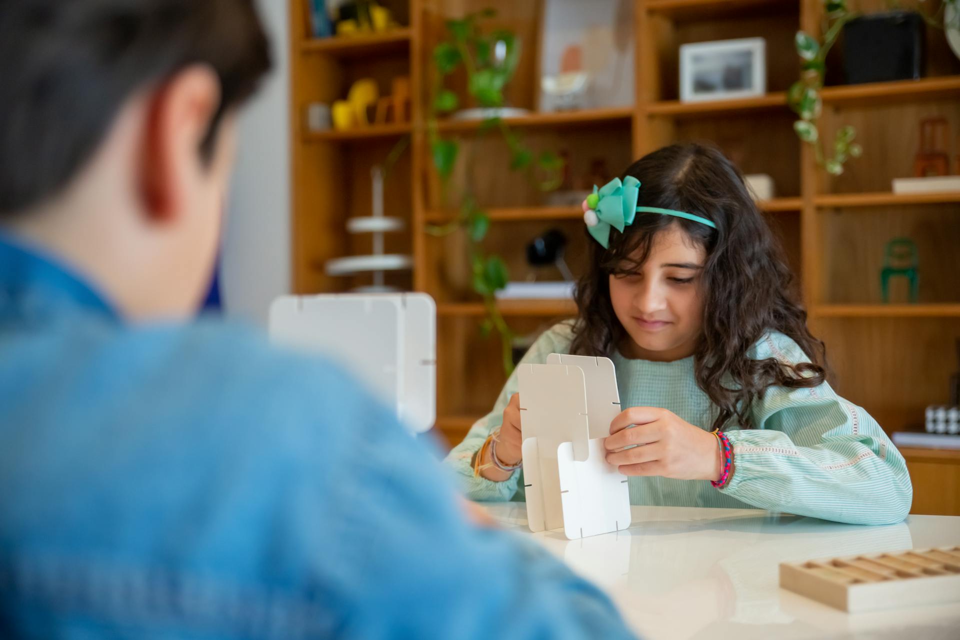 Two children creatively assembling cardboard models in a bright, engaging classroom setting.