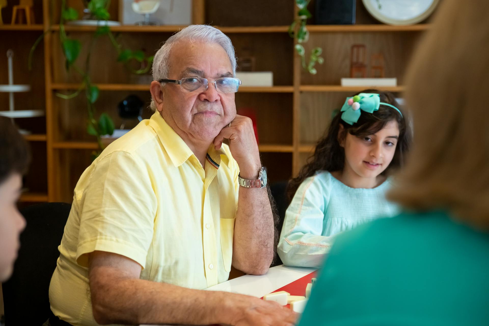 An elderly man with grandchildren enjoying family time at home.