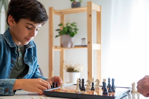 Free Boy in Denim Jacket Playing Chess Stock Photo