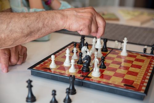 Free A close-up of an adult playing chess indoors on a patterned board. Stock Photo