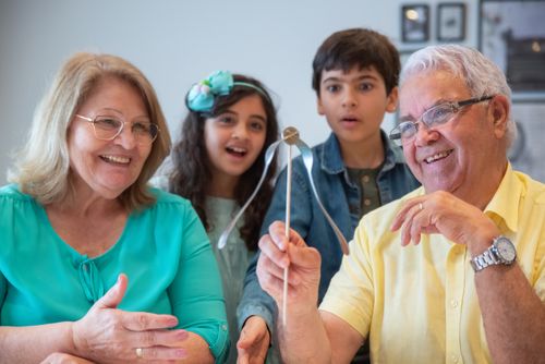 Free Smiling grandparents enjoying playful moments with their grandchildren indoors. Stock Photo