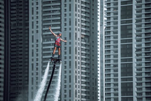 A Man Riding a Flyboard with Building Background