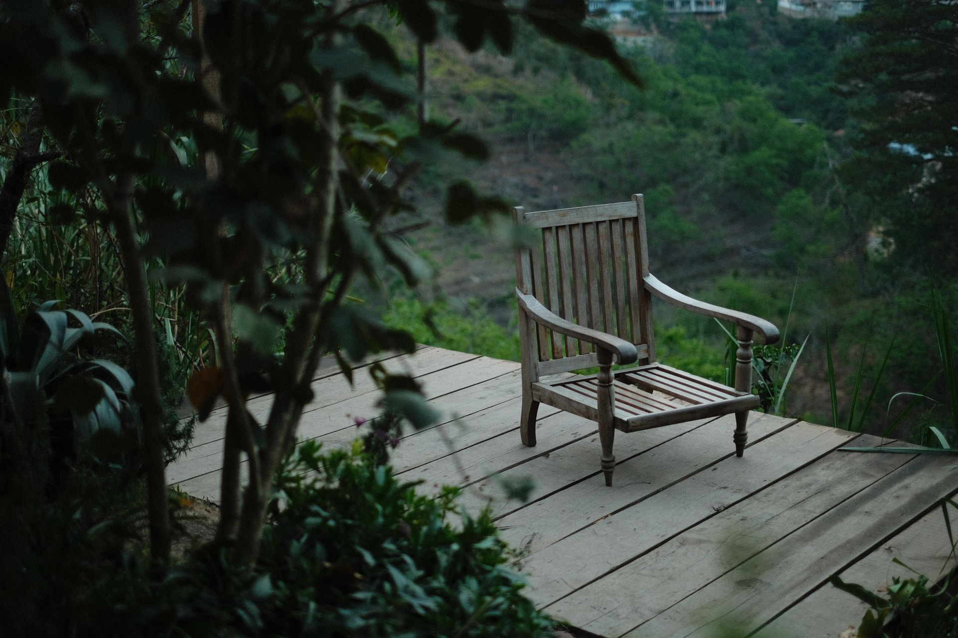 Wooden chair on a deck with lush green valley view, offering a relaxing outdoor retreat.