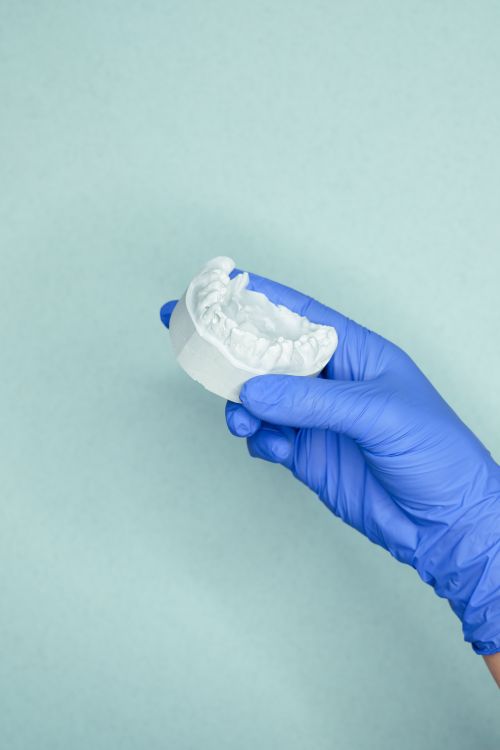 Free Close-up of a dental mold held by a blue gloved hand against a light background. Stock Photo