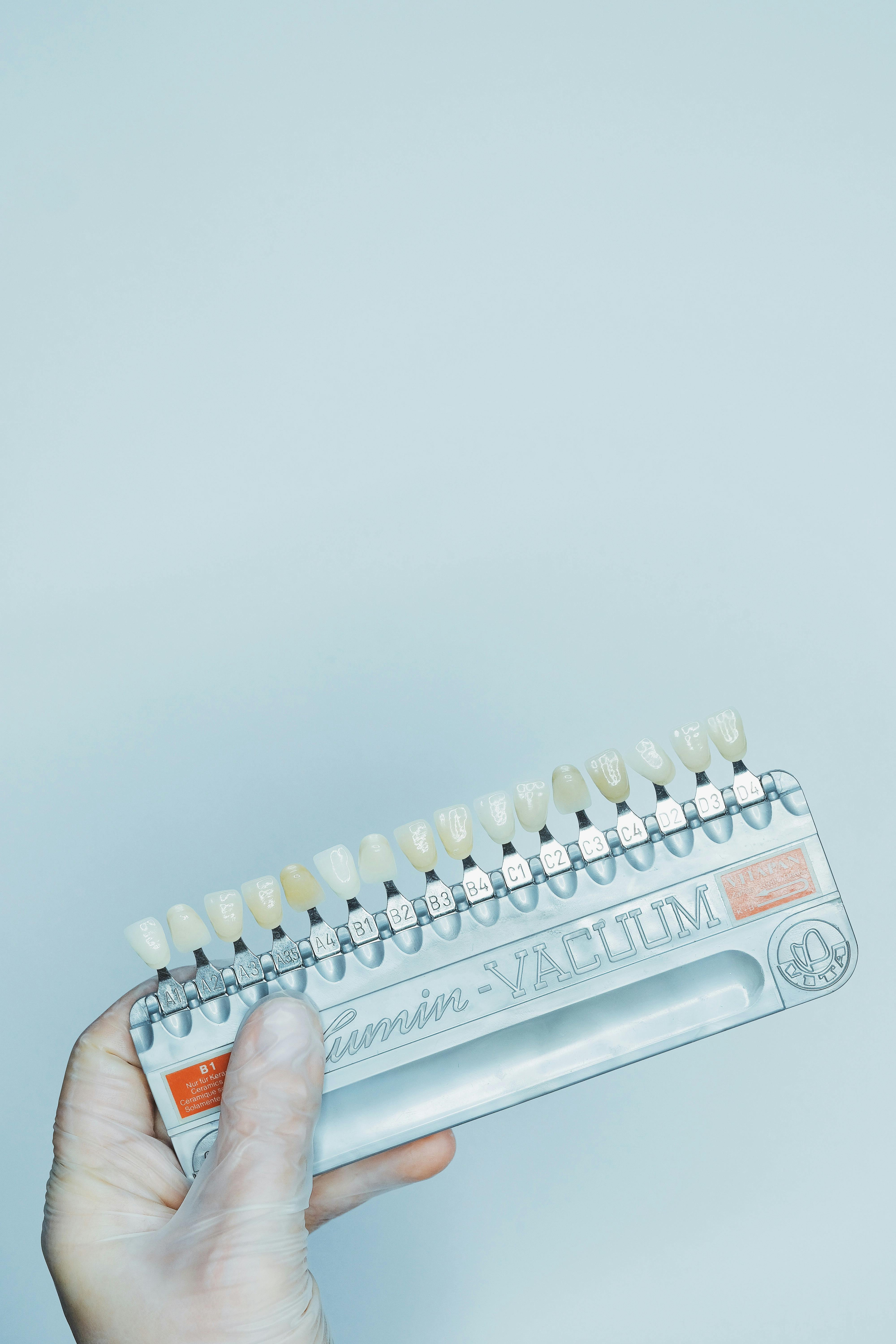 Close-up of a hand holding a dental shade guide with clear copyspace.