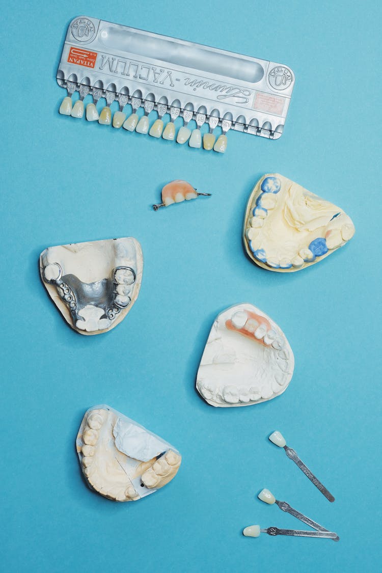 Teeth Moulds And Veneers Scattered On Blue Background 