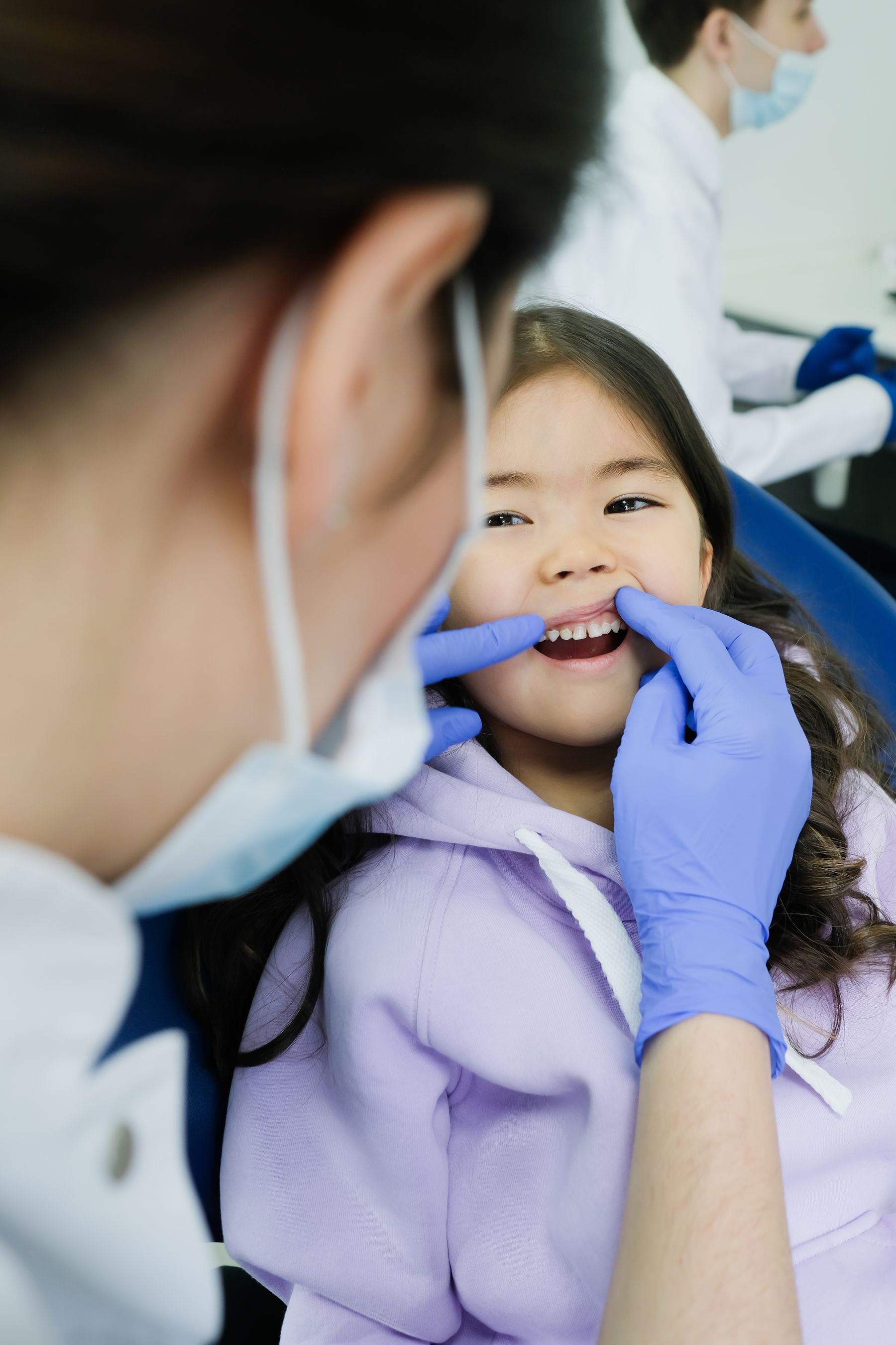 Dentist checking a young patient while a parent stays nearby