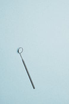 Dental mirror isolated on a textured light blue background with ample copy space.
