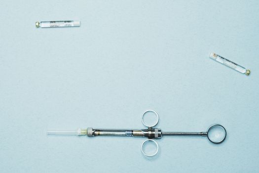 High-quality stock photo of a dental syringe and vials on a blue background. Ideal for dentistry.