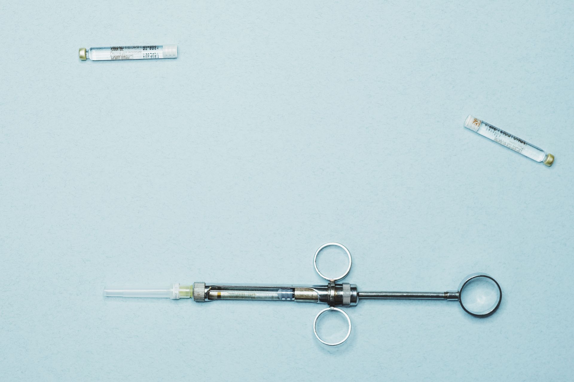 A hospital syringe and vial on a blue surface