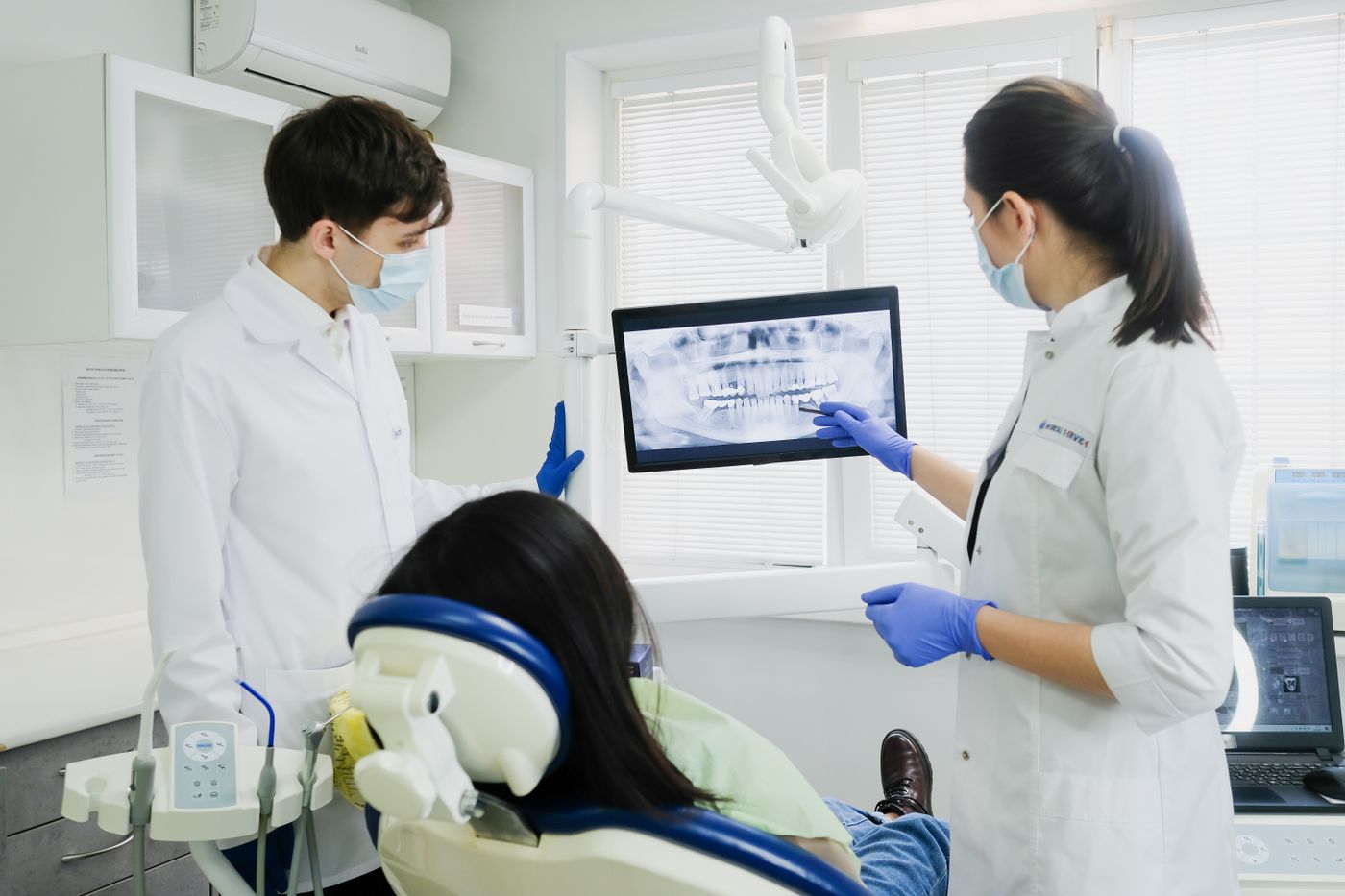 Dos odontólogos revisando una radiografía panorámica en una pantalla junto al sillón dental