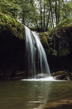 Tranquil waterfall cascading in a lush green forest setting, creating a serene and picturesque scene.