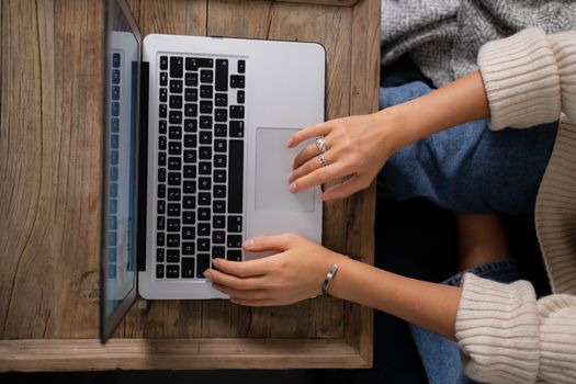 A woman typing on a laptop at a rustic wooden table, showcasing productivity and work from home.