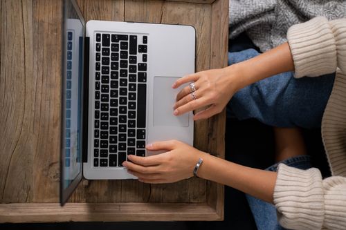Free A woman typing on a laptop at a rustic wooden table, showcasing productivity and work from home. Stock Photo