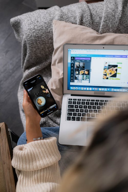 A Person in a Sweater Using a Laptop and a Smartphone