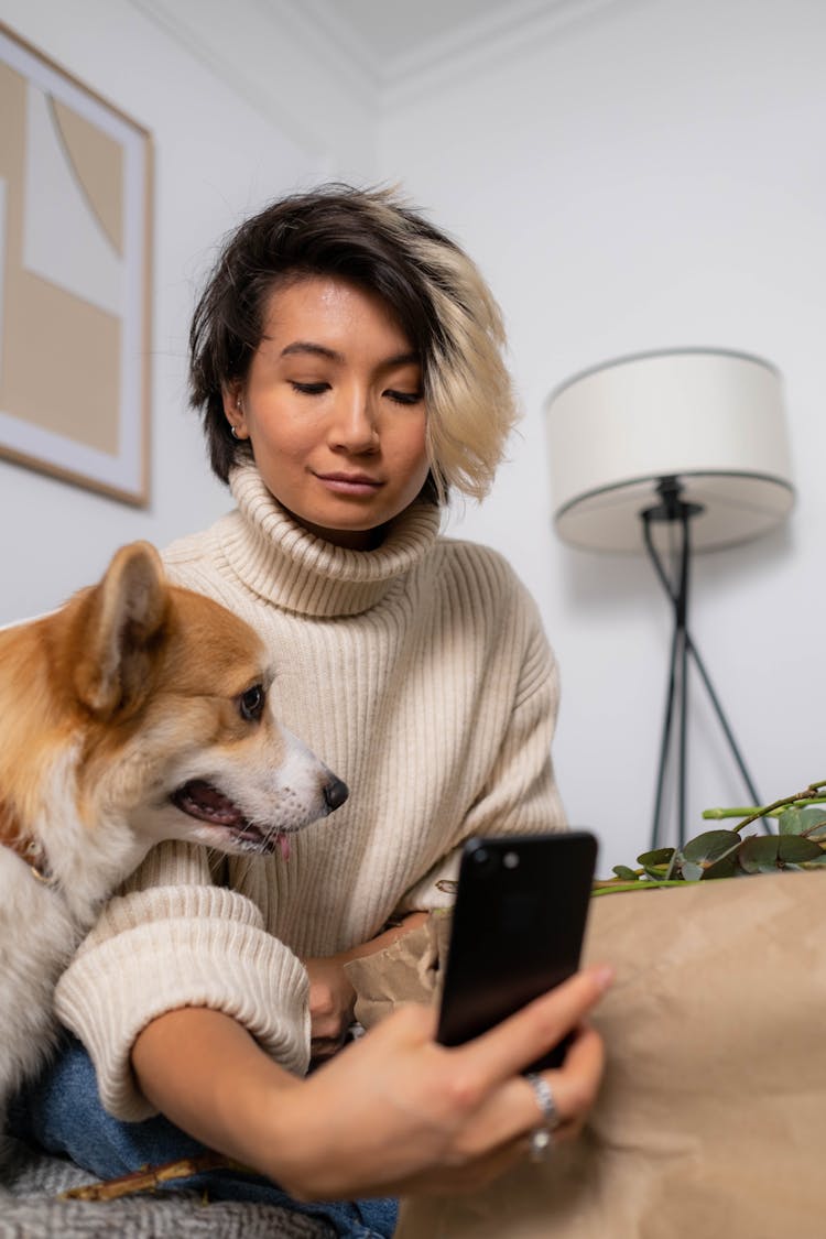 A Woman In A Sweater Taking A Selfie With Her Pet Dog