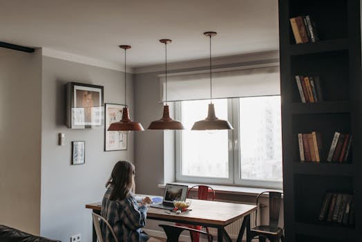 A woman working on a laptop in a stylish, cozy apartment with modern decor.