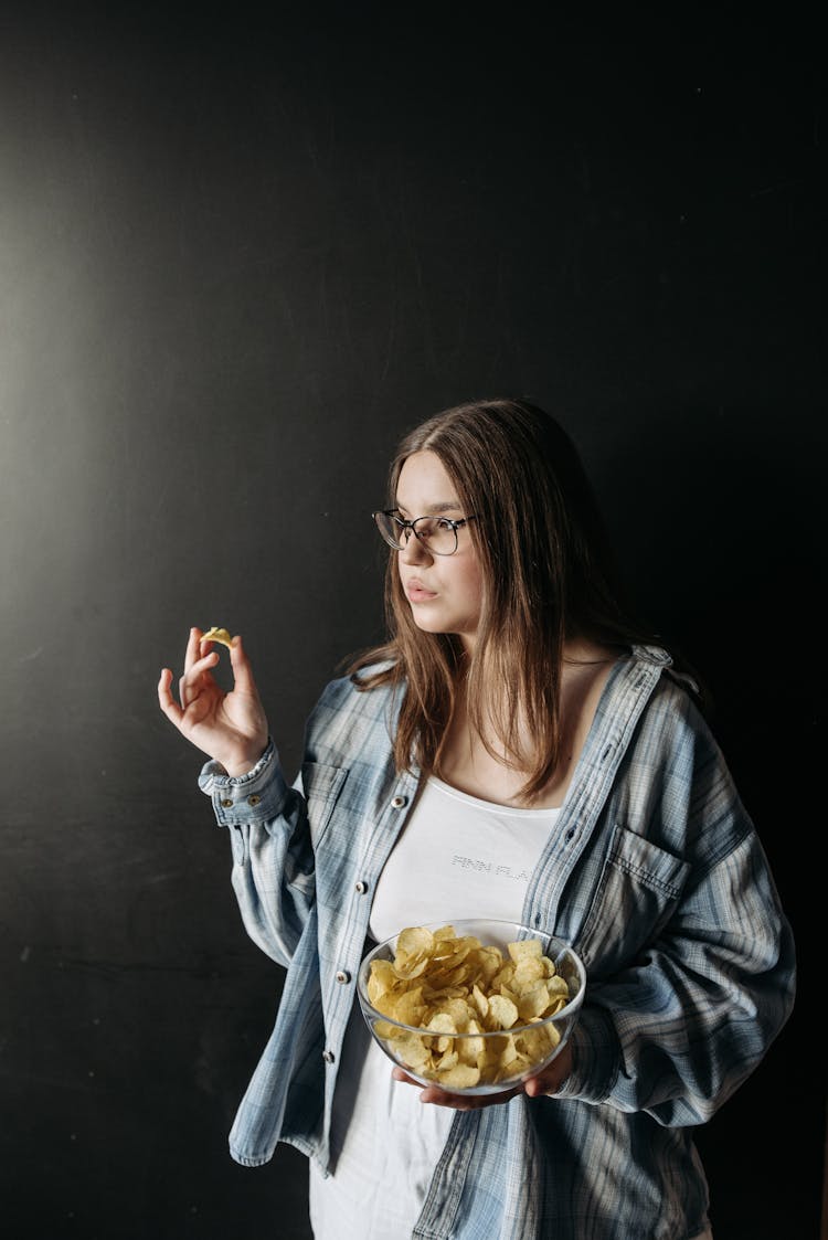 A Woman Eating A Bowl Of Chips 