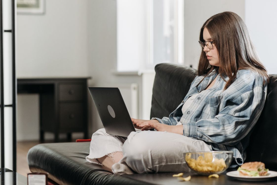 Woman Using Laptop while Sitting on Black Sofa · Free Stock Photo