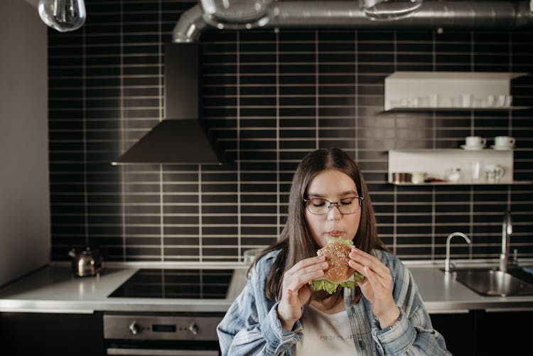 Woman In Blue And White Plaid Long Sleeve Shirt Eating A Burger