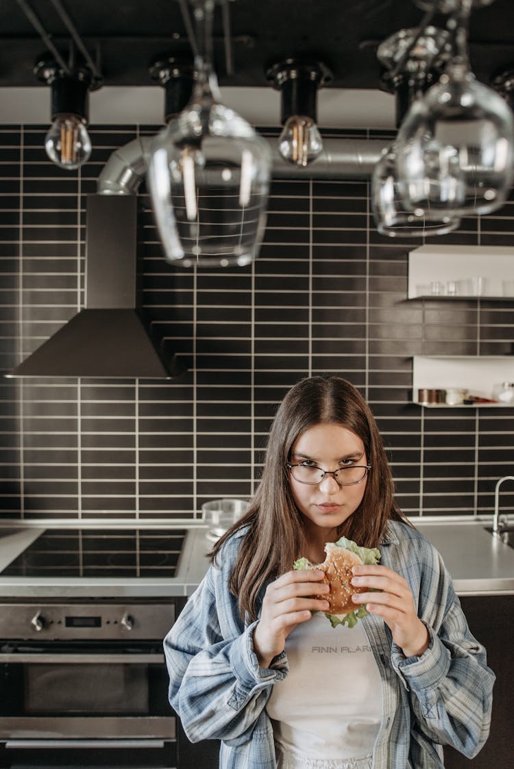 Woman Standing In The Kitchen Eating A Delicious Sandwich 