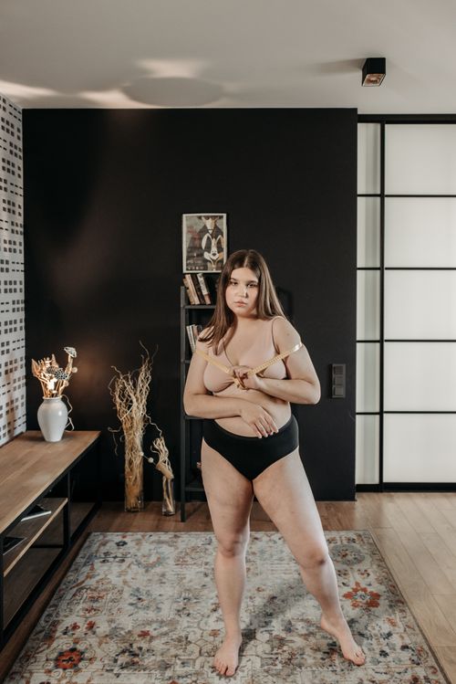 Free Elegant portrait of a plus-size woman in fashionable lingerie, standing confidently in a stylish interior setting. Stock Photo