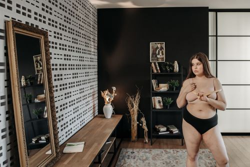 Free Plus size woman measuring body size in modern chic room reflecting self-acceptance and positivity. Stock Photo