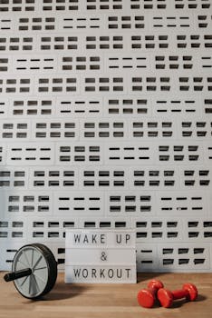 Inspirational workout space featuring dumbbells, ab roller, and motivational sign.