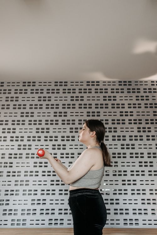 Free A woman performs a strength workout with a dumbbell in a modern gym setting, promoting fitness. Stock Photo