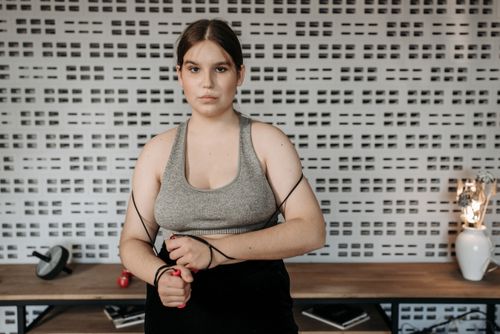 Free Focused young woman holding a jump rope in a modern indoor gym setting. Stock Photo