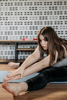 Young woman in a yoga pose stretching on a mat inside a room.