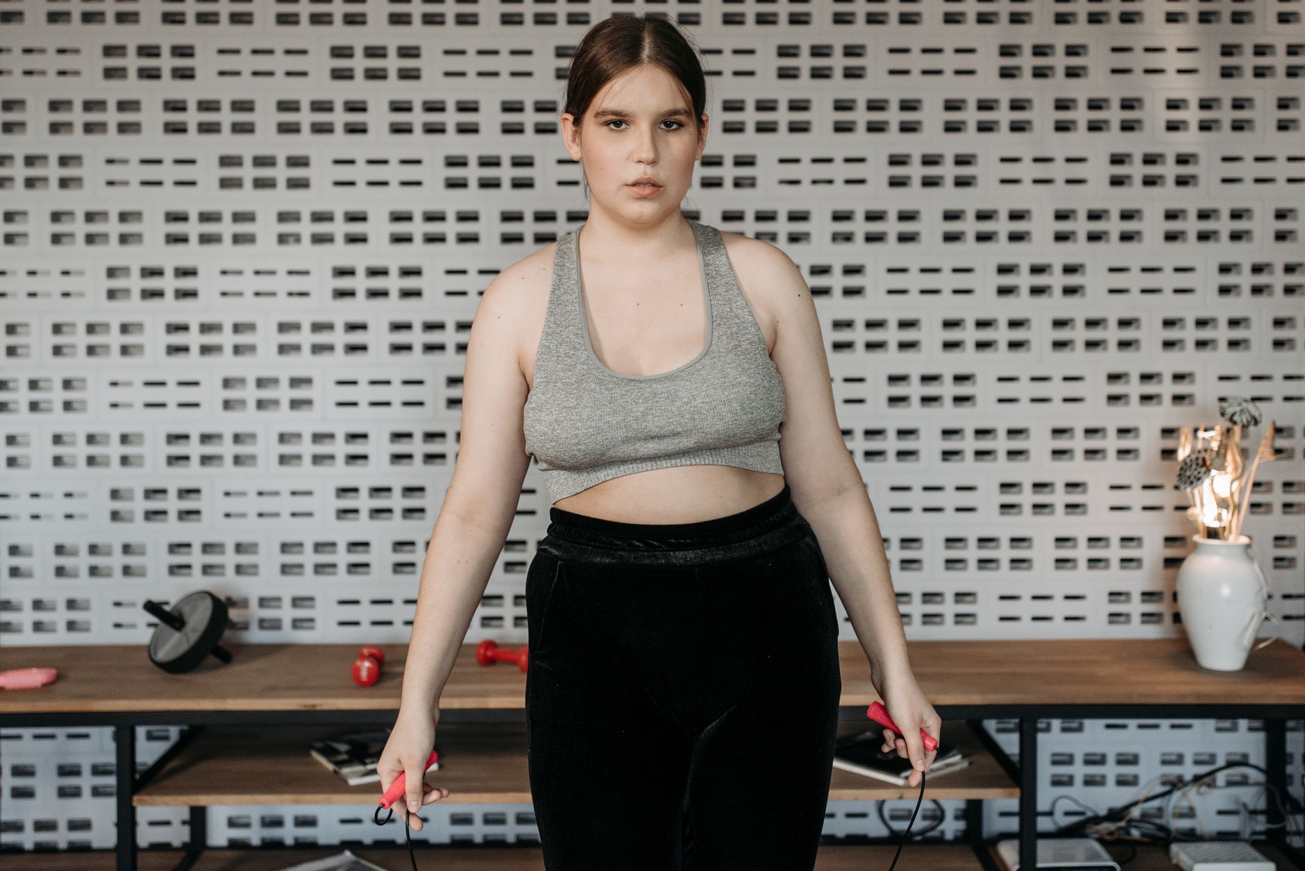 long covid natural weight loss women — Confident woman in sporty attire using a jump rope indoors. Fitness and exercise concept.