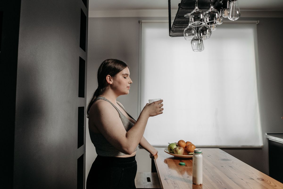 Woman enjoying a smoothie in a bright kitchen