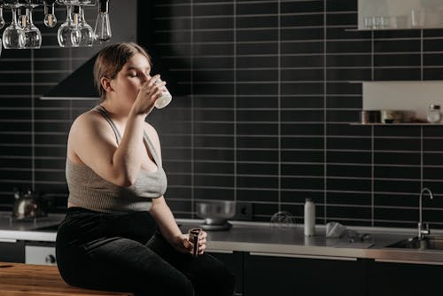 Free Woman Sitting on Table and Drinking Milk Stock Photo